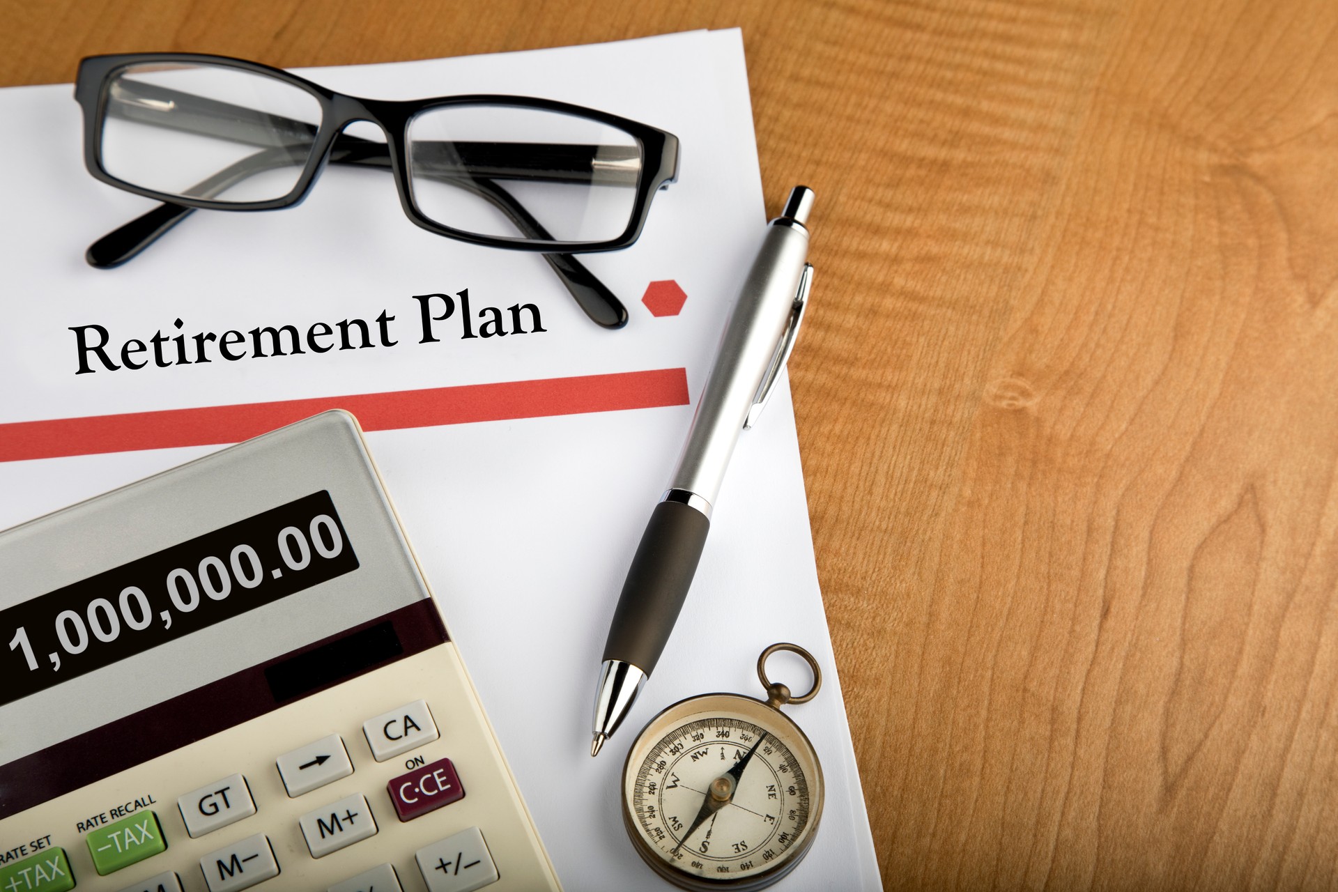 Retirement Plan documents with calculator, pen, compass, and glasses