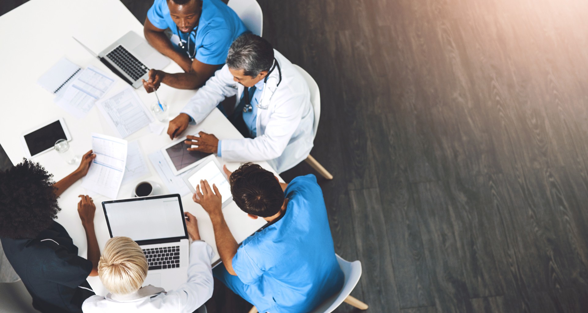 Medical team, technology and meeting in office from above, paperwork and budget in hospital. Men, women and specialist at table for brainstorming, healthcare and financial planning in boardroom