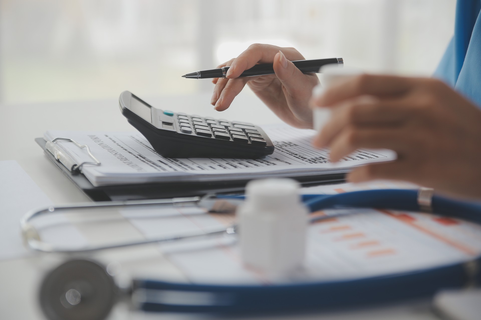 Doctor or physician using calculator and work on laptop computer with medical stethoscope on the desk at clinic or hospital. Medical healthcare costs ,fees and revenue concept.