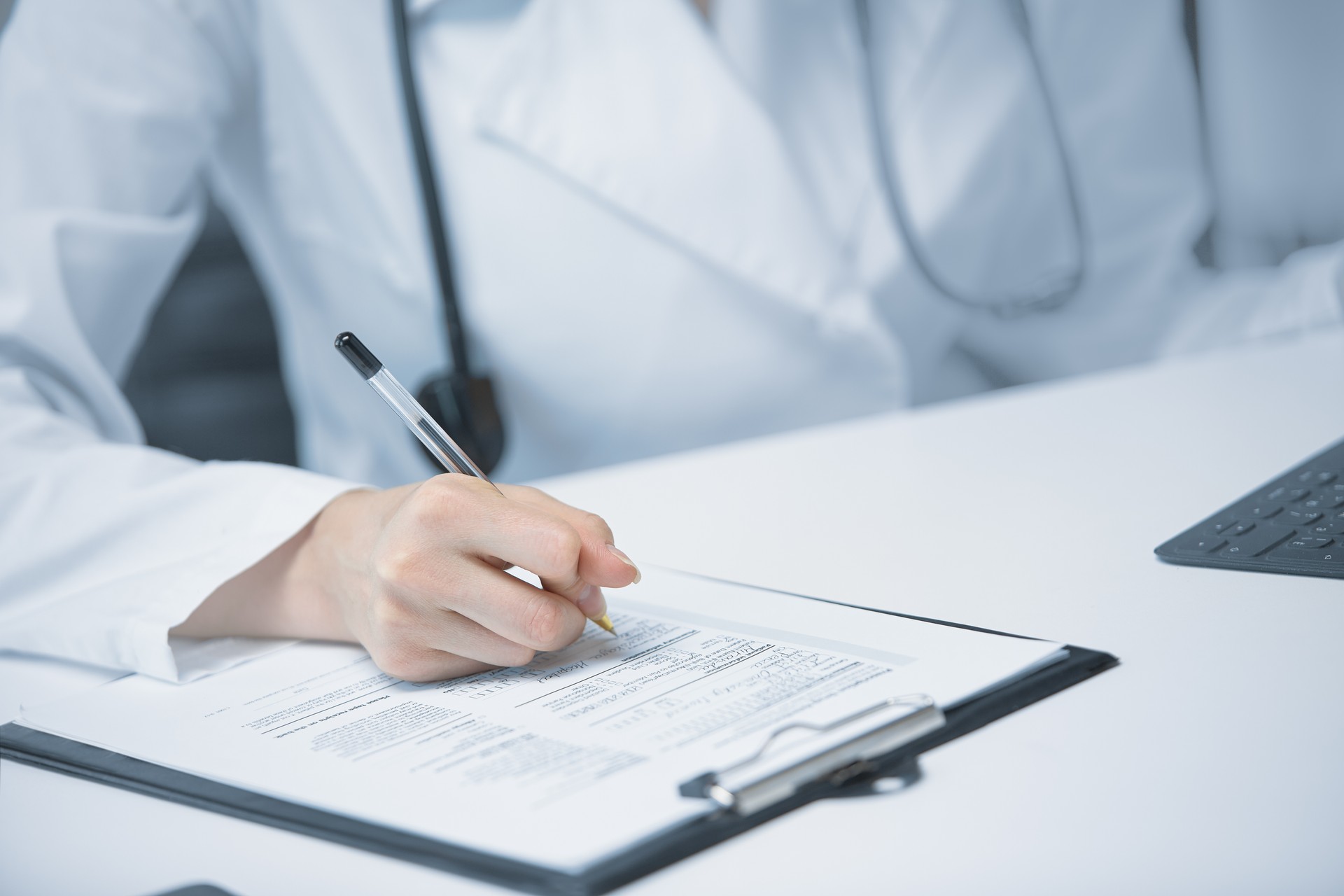 Close up of a hand with a pen signing a document by a medical professional